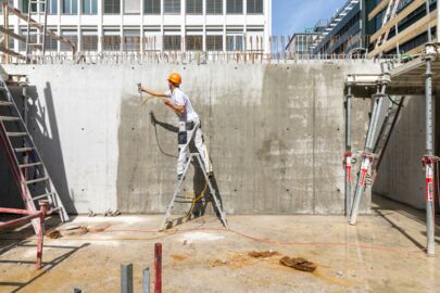 Arbeiter auf einer Leiter beim Auftragen der Schutzschicht PSS 20 gegen Graffiti auf der Baustelle